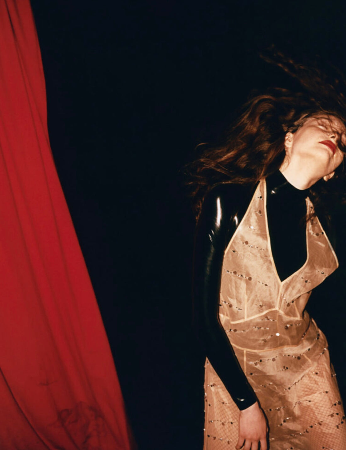 Red curtain with a girl caught in action moving her hair around